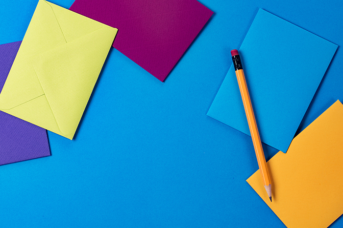 A yellow pencil with envelopes on a clean, blue backdrop!